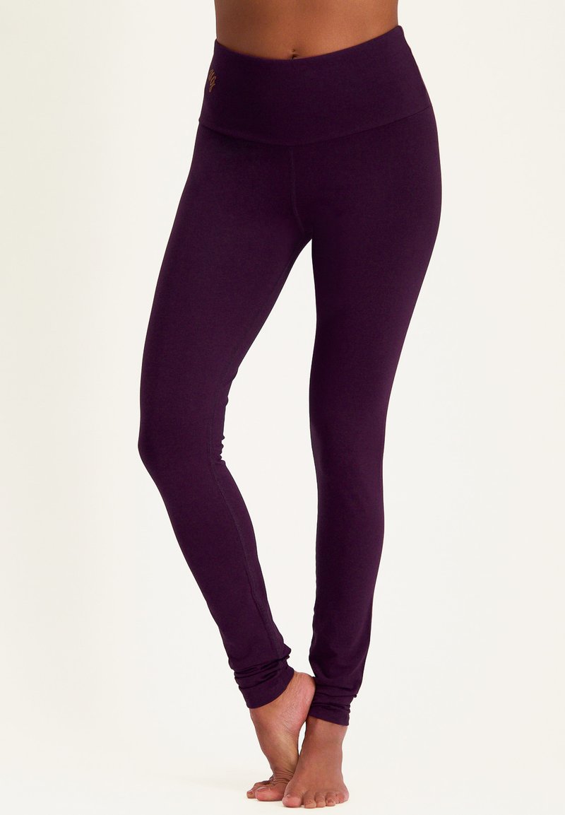 Lila Leggings mit einem breiten, weichen Bund. Hergestellt aus glattem Stoff, mit einer figurbetonten Passform und nahtlosen Knöcheldetails.