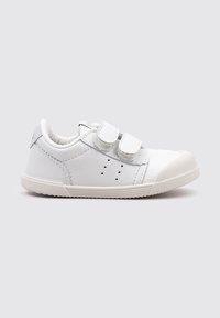 Zapatilla blanca de cuero con dos tiras de Velcro, puntera redonda y detalles perforados en los laterales. Suela de goma en contraste con la parte superior.