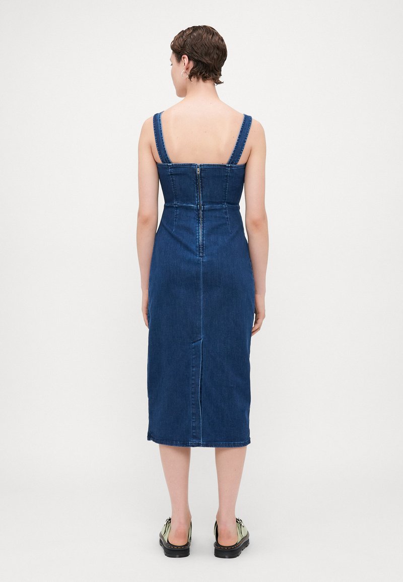 Denim-Midi-Kleid mit breiten Trägern, taillierten Oberteil und einem Reißverschluss hinten in der Mitte. Dunkelblaue Farbe mit dezenten Nähdetails. Flacher Saum.