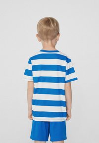 Le t-shirt rayé présente des rayures horizontales bleues et blanches, en coton, avec un col rond, des manches courtes, associé à un short bleu uni.