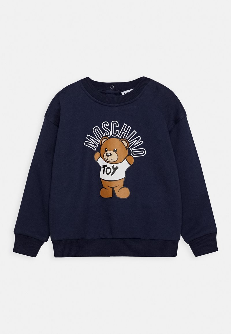 Sweat-shirt bleu marine avec un ours en peluche portant une chemise blanche sur laquelle est écrit "jouet" et le mot "Moschino" au-dessus de l'ours.