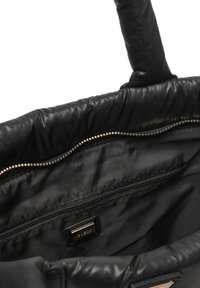 Interno di una borsa imbottita nera con una tasca con cerniera dorata e un'etichetta del marchio visibile nel rivestimento.