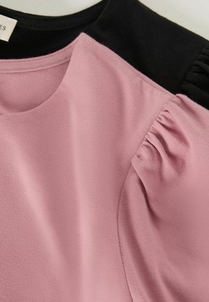 Růžový top s černými akcenty. Měkká tkanina, kulatý výstřih a nařasené detaily na rukávech. Hladký povrch, lehký design.
