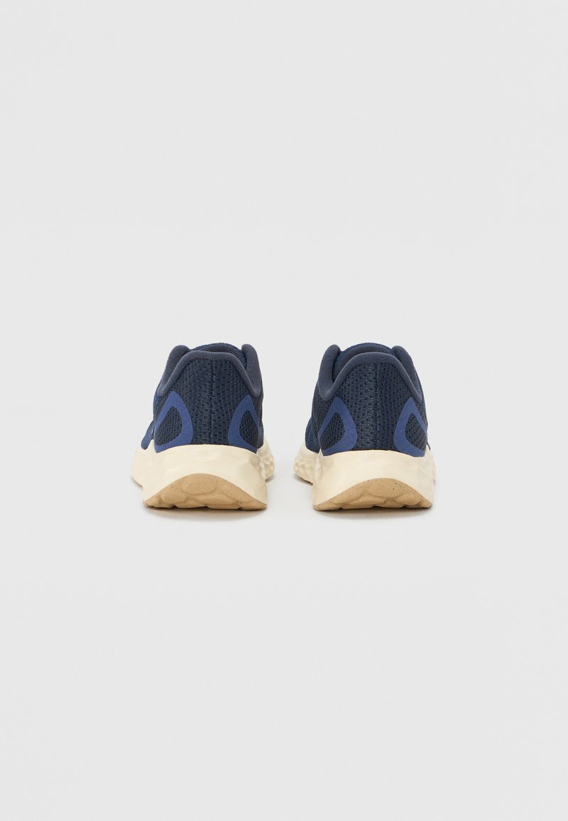 Scarpe da ginnastica in rete navy con suole beige chiaro, caratterizzate da una parte superiore testurizzata e accenti blu a contrasto sui lati e sul tallone.