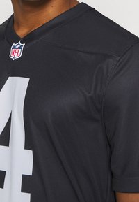 Jersey negro de la NFL hecho de un material sintético suave, con el número '4' en blanco destacado y un logo de la NFL en el cuello.