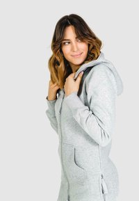 Grijze rits-hoodie met zakken, gestructureerde stof en een gevoerde capuchon. Strak ontwerp met subtiele branding aan de voorkant.