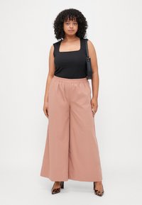 Mustat neliökaula-aukkoiset tanktopit yhdistettynä löysiin vaaleanpunaisiin leveisiin lahkeisiin housuihin. Elegantti rakenne joustavalla vyötärönauhalla ja hienovaraisella laskoksella.