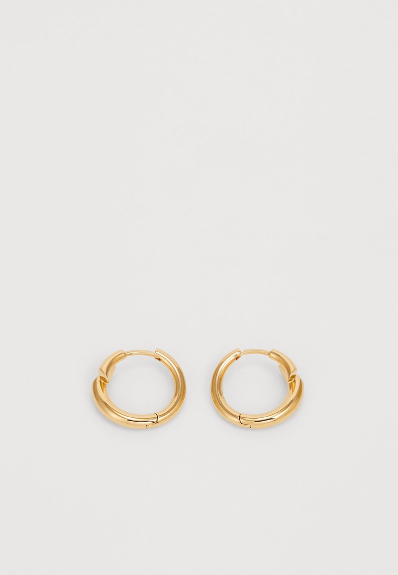 Auksinės spalvos žiedinės auskarai su blizgiu paviršiumi, storu dizainu ir užsegimu, kuris palengvina dėvėjimą.