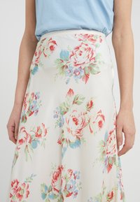 Gonna maxi floreale in tessuto leggero, con grandi motivi di rose rosse e blu su sfondo crema, con una finitura liscia e vita elastica.