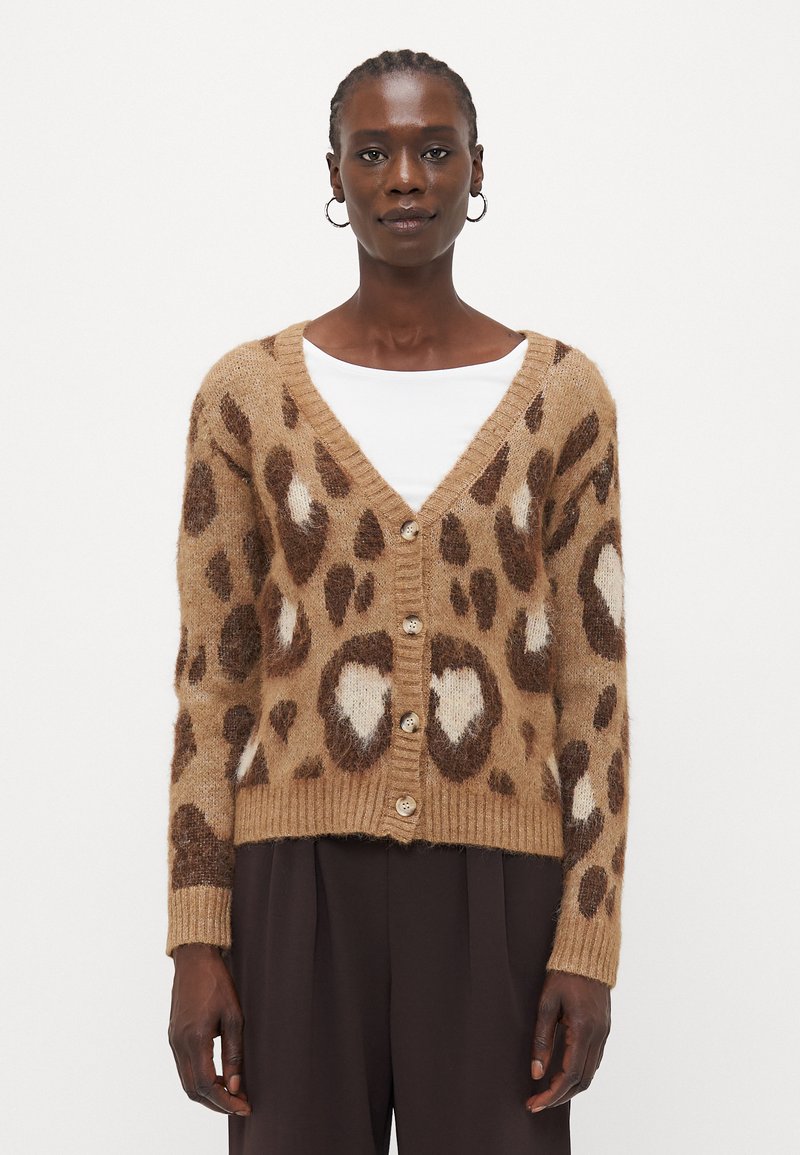 Leopardmønstret cardigan i en tanfarve med brune og hvide detaljer. Har en V-halsudskæring, fem knapper og ribbede manchetter. Blød tekstur.