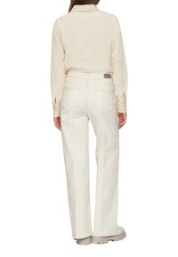 Chemise blanche à manches longues associée à un pantalon blanc à jambes larges. L'ensemble présente un design simple et des détails de couture subtils.