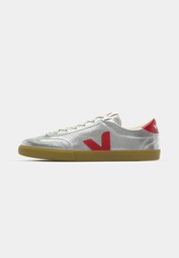 Silver sneakers with red accents, textured upper, beige laces, and rubber sole. Features a striking V logo on the side.