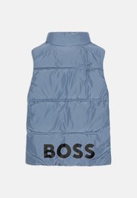 Padded bezrukavni prsluk svijetloplave boje, s visokim okovratnikom i velikim crnim "BOSS" logotipom na leđima. Glatka, sjajna tekstura sa horizontalnim šavovima.