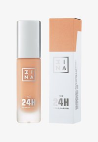 24H foundation i en transparent flaska med ett silverlock. Lådan är vit med orangea accenter och fet text med produktinformation.