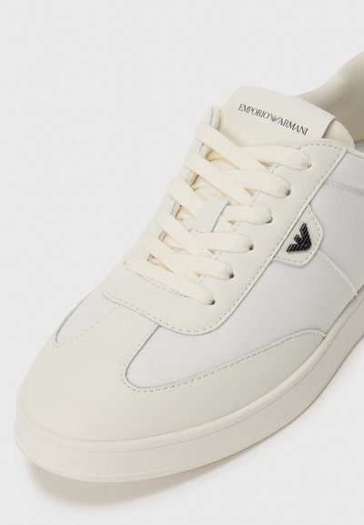 Valge Emporio Armani jalanõud, seotud paeltega, logo keeles ja külgedel, sileda nahast ja kangast ülemine osa, lähivõte.