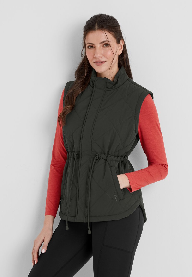 Dark green quilted vest with a high collar, adjustable drawstring waist, and pockets, paired with a long-sleeve red top and black pants.