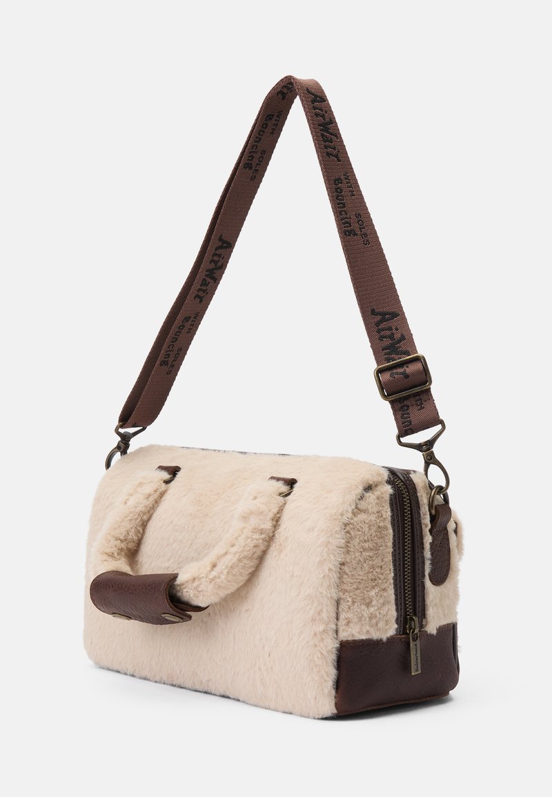 Bolso de piel sintética con un cuerpo crema y acentos de cuero marrón, con doble asa y una correa desmontable con texto impreso, cierre de cremallera.