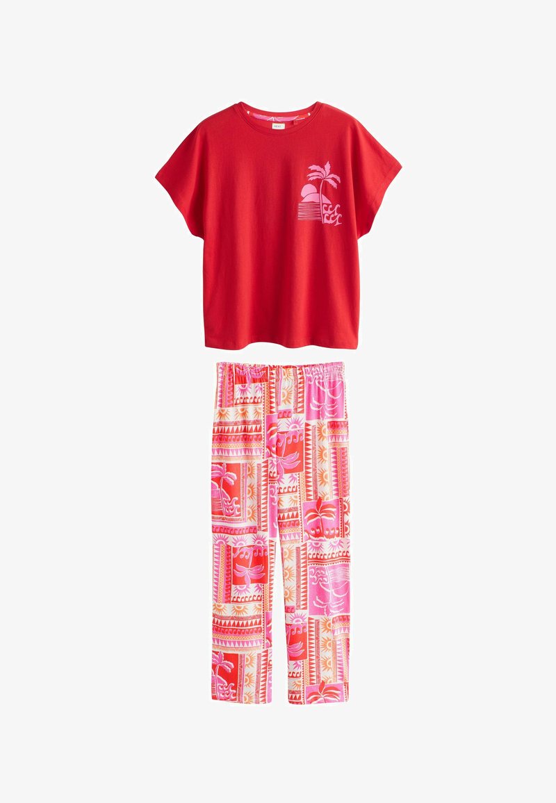 Rood kort shirt met korte mouwen en een roze tropische afbeelding, gecombineerd met wijde broekspijpen in roze, rood en oranje met tropische motieven.