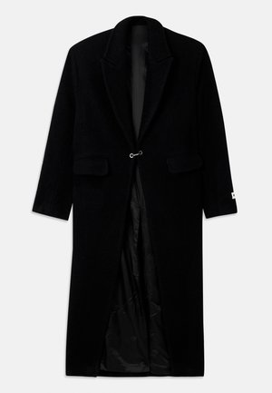 Schwarzer Wollmantel mit langer Silhouette, Reverskragen, zwei Fronttaschen und einer silbernen Knopfverschluss. Glatte schwarze Innenauskleidung.