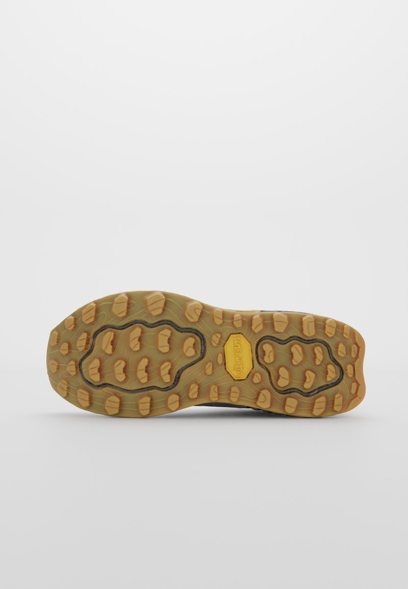 Suela de zapatilla de trail running con un diseño resistente que presenta una suela de goma segmentada y con patrón en tonos amarillos y gris oscuro.