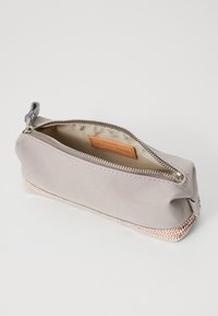 Grå canvas pennfodral med en strukturerad rosegoldbotten. Utrustad med en silvrig dragkedja och en beige inredning med en läderlogg.