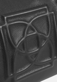 Zwarte leren tas met een getextureerd oppervlak en een opvallend reliëf geometrisch patroon, met fijne details en diepte.