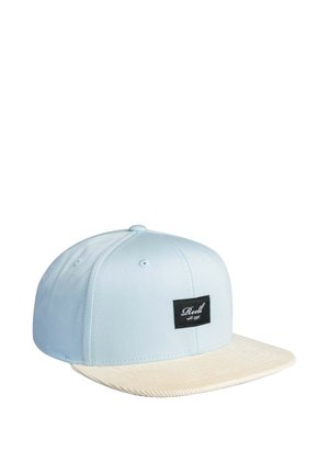 Light blue snapback cap with cream-colored flat brim and black rectangular logo patch reading "Reell est. 1997" on front panel.