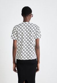 Majica s kratkim rukavima s uzorkom crno-bijelog šahovskog uzorka i ponovljenim natpisom "NY", izrađena od mekog materijala.