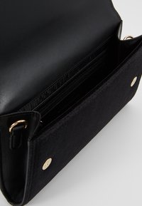 Svart handväska med en kombination av slät läder och mjukt mocka. Inuti finns flera kortfack och ett ficka med dragkedja. Guldiga detaljer.