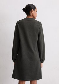 Robe longue à manches longues de couleur vert foncé, en tissu doux, avec un col rond, une coupe décontractée et un ourlet qui tombe au-dessus des genoux.