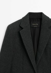 Villapaita harmaasta villasta, jossa on leikkauslapel, hentoinen tekstuuri ja etiketti, jossa lukee "Massimo Dutti". Sujuva sisävuori.