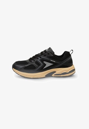 Scarpa sportiva nera con una tomaia in rete, dettagli testurizzati e una suola in gomma color nocciola con un design a ondulazione. Include lacci e un manico di estrazione.