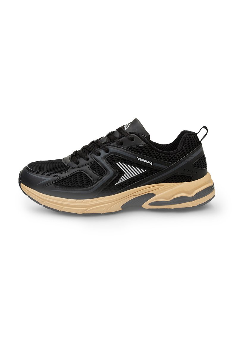 Scarpa sportiva nera con una tomaia in rete, dettagli testurizzati e una suola in gomma color nocciola con un design a ondulazione. Include lacci e un manico di estrazione.