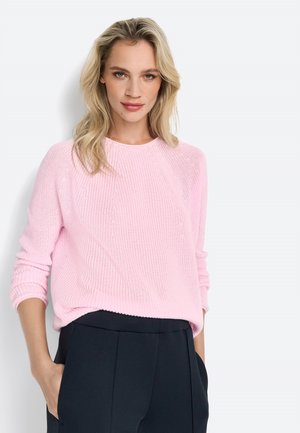 Light pink knit sweater with ribbed texture, crew neckline, and long sleeves, paired with black high-waisted trousers.