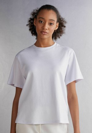 Hvid bomulds t-shirt med afslappet pasform, rund halsudskæring og korte ærmer. Glat tekstur med subtil glans, minimalistisk design.