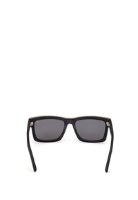 Černé obdélníkové sluneční brýle s tmavými skly, silnými plastovými rámy a jemným zlatým akcentem na horní části. Mají mírně zahnuté straničky.