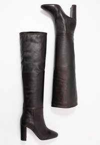 Sorte læderstøvler, der går over knæet, med glat tekstur, spids tå og en tyk blokhæl. Har et tætsiddende design uden udsmykning.