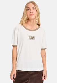 Witte T-shirt met korte mouwen en olijfgroene geribbelde kraag en boorden. Heeft een centrale grafische afbeelding in gedempte kleuren. Gemaakt van katoen, ontspannen pasvorm.