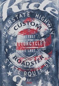 Camiseta azul con un estampado desgastado que presenta gráficos temáticos de motocicletas en rojo y blanco, estrellas y texto en varias tipografías.