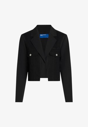 Veste noire raccourcie avec un design structuré, dotée d'un col pointu, de poches poitrine à pression et de détails de couture visibles.