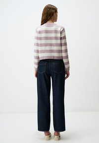 Maglione cropped a righe viola e bianche abbinato a jeans a gamba larga blu scuro. Il maglione presenta un collo rotondo e polsini a coste.