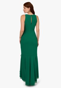 Zelené večerní šaty s přiléhavým korzetem, rozšířeným lemem a detaily ve tvaru klíčové díry na zádech. Vyrobeny z hladkého materiálu s jemnou texturou.