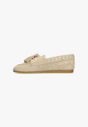 Beige suede loafer with tassels on top, heart-shaped cutouts along the side, and a flat rubber sole.