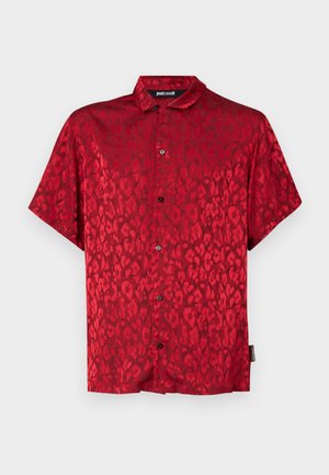 Punane lühikeste varrukatega särk leopardimustriga, valmistatud siledast materjalist. Omab nööpidega kinnitatavat esiosa ja klassikalist kaeluse disaini.