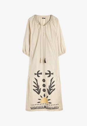 Beżowa bawełniana sukienka z rękawami do łokcia, dekoracyjnym czarnym haftem, zapinana na guziki z frędzlami i motywem słońca na dole.