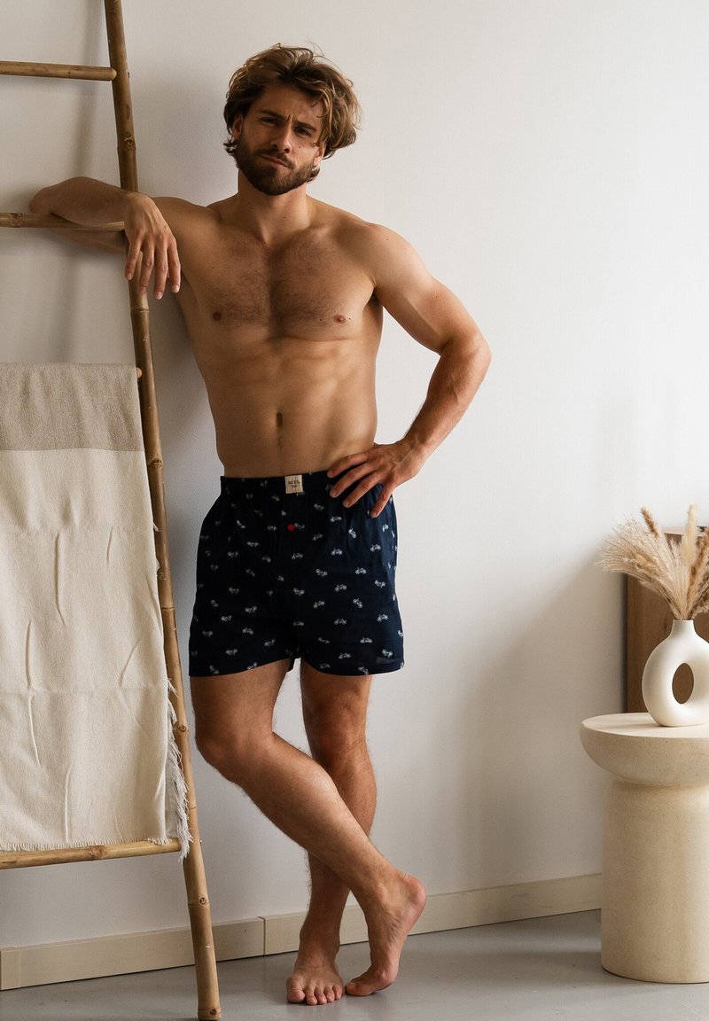 Boxer da uomo blu navy con motivo a biciclette, dotati di una cintura elastica e apertura frontale, realizzati in tessuto leggero.