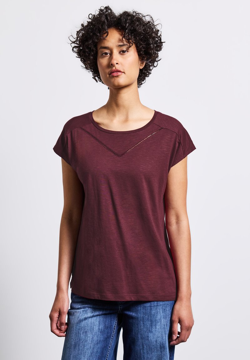 T-shirt bourgogne à manches courtes avec un col rond et un accent en découpe triangulaire juste en dessous des épaules, en tissu doux et léger.