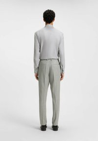 Ljusgrå långärmad skjorta med subtil lyster, som matchas med grå kostymbyxor med smal rand. Outfiten har en skräddarsydd passform och slät textur.