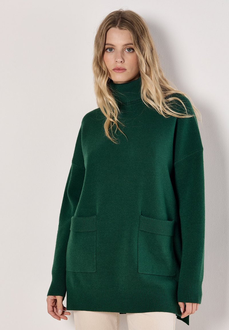 Grüner, gestrickter Oversize-Pullover mit rollkragen, überschnittenen Schultern, gerippten Bündchen, zwei Fronttaschen und einer entspannten Passform.