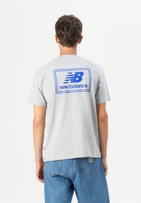 Grå bomull T-skjorte med en blå "New Balance" logo på ryggen, med korte ermer og en avslappet passform.